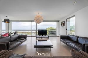 ein Wohnzimmer mit Ledersofas und einem Flachbild-TV in der Unterkunft Casa das Areias - Surf, Golf and a wonderful sea view in Areia Branca