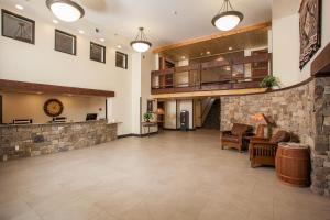 a large lobby with a stone wall and chairs and tables at Red Feather Lodge/Hotel in Tusayan