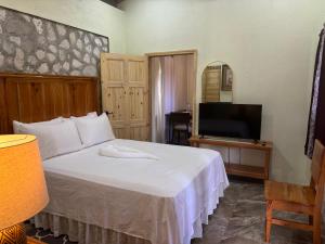 ein Schlafzimmer mit einem weißen Bett und einem Fernseher in der Unterkunft The Ridge - Stone Cottage in Buff Bay