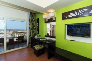 a room with a green wall with a television and a table at Rosa Boho Hotel And Aqua Park in Hurghada