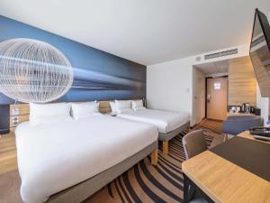 um quarto de hotel com duas camas e uma escrivaninha em Novotel Kraków Centrum na Cracóvia