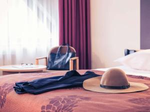 a hat on top of a bed with a dress at Mercure Jelenia Góra in Jelenia Góra