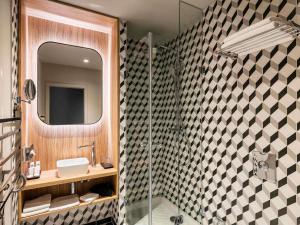 a bathroom with a shower and a sink and a mirror at Century Old Town Prague - MGallery Collection in Prague