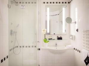 a white bathroom with a sink and a shower at Century Old Town Prague - MGallery Collection in Prague