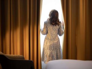 Une femme en robe qui regarde par une fenêtre dans l'établissement Century Old Town Prague - MGallery Collection, à Prague