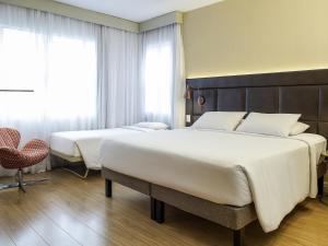 a hotel room with two beds and a chair at Mercure Sao Paulo Jardins in Sao Paulo