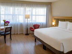 a hotel room with a large bed and a desk at Mercure Sao Paulo Jardins in Sao Paulo