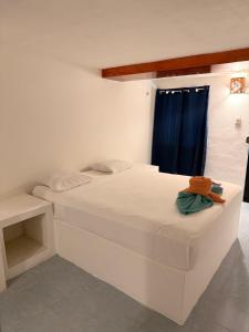 a bedroom with a white bed with a blue curtain at Hotel Chuburna in Chuburná