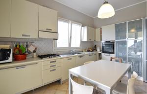 une cuisine avec des armoires blanches et une table blanche dans l'établissement Pet Friendly Home In Vallecrosia, à San Biagio della Cima