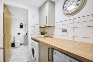 eine Küche mit einer Waschmaschine und einer Uhr an der Wand in der Unterkunft Estcourt Avenue Apartments in Headingley