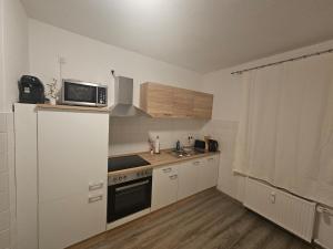 a small kitchen with white cabinets and a microwave at Zentrale & gemütliche Wohnung in Wolfsburg in Wolfsburg +11 photos