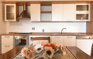 eine Küche mit weißen Schränken und einem Tisch mit Blumen darauf in der Unterkunft 1 Bedroom Nice Apartment In Sant'angelo In Vado in Piandimeleto