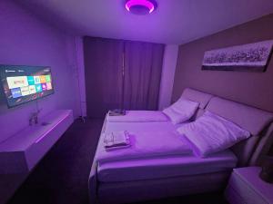 a purple room with a bed and a tv at Zentrale & gemütliche Wohnung in Wolfsburg in Wolfsburg
