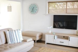 een woonkamer met een bank en een klok aan de muur bij Bombo Beach House in Kiama