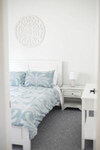 een witte slaapkamer met een bed en een wit bureau bij Bombo Beach House in Kiama