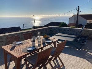 a wooden table and chairs with a view of the ocean at Casabelavista Iii in Fajã do Araújo