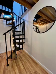 a spiral staircase with a round mirror on the wall at NYC-Style Loft with Secret Entrance - Just 6 Miles from Times Square in North Bergen +2 photos