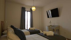 a bedroom with two beds and a television on the wall at Hotel Rural Mirador de Jubrique in Jubrique