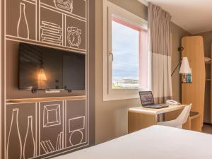 a room with a bed and a desk and a window at ibis Genève Aéroport in Geneva +106 photos