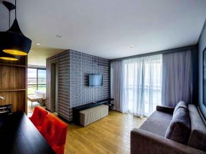 ein Wohnzimmer mit Sofa und Fernseher in der Unterkunft Grand Mercure Brasilia Eixo Monumental in Brasilia