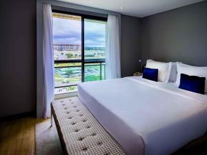 ein großes weißes Bett in einem Zimmer mit einem großen Fenster in der Unterkunft Grand Mercure Brasilia Eixo Monumental in Brasilia