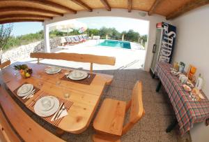 a wooden table and chairs in a room with a pool at Geräumige Ferienvilla Mit Pool Und Meerblick in Grohote