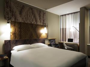 a bedroom with a large white bed and a desk at Ibis Den Haag City Centre in The Hague