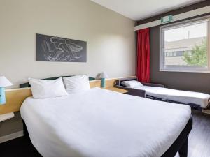 a hotel room with two beds and a window at Ibis Madrid Getafe in Getafe