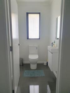 a white bathroom with a toilet and a sink at Homestead Hideaway in Ohoka in Ohoka +11 photos