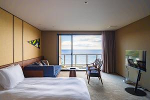a hotel room with a bed and a view of the ocean at IZU RETREAT by Onko Chishin in Higashiizu