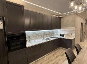 a kitchen with dark brown cabinets and a sink at Delux Apartment Dmytro in Ternopilʼ