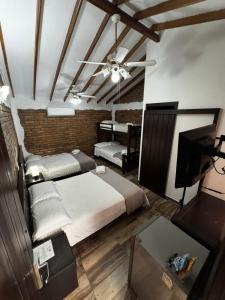 a bedroom with two beds and a tv and a brick wall at Hotel Boutique Colonial Cartago in Cartago +58 photos