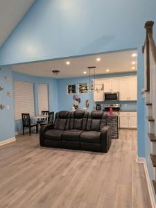 a living room with a black couch and a kitchen at Work and play close to everything in Frederick