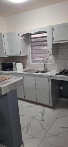 una cucina con mobili bianchi, un lavandino e una finestra di Cozy Peaceful Haven on Hilltop a Saint Martin
