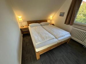 una camera da letto con un letto con due comodini e una finestra di Ferienhäuschen Seekrabbe a Baltrum