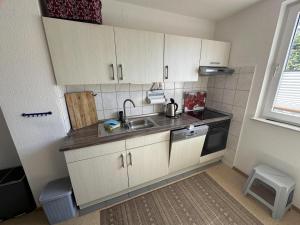 una piccola cucina con armadi bianchi e lavandino di Ferienhäuschen Seekrabbe a Baltrum