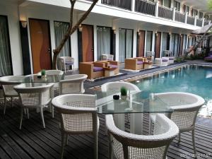 a patio with tables and chairs next to a swimming pool at Serela Kuta by KAGUM Hotels in Kuta