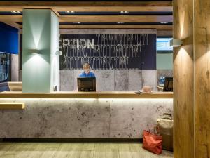 a person sitting at a computer in a lobby at Ibis Budget Graz City in Graz