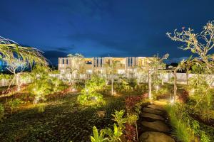 Snow White Villas 3BR Haven Near Pandawa Beach في أونغاسان: حديقة بها أضواء أمام المبنى