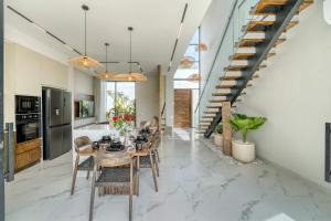 Snow White Villas 3BR Haven Near Pandawa Beach في أونغاسان: مطبخ وغرفة طعام مع طاولة وكراسي