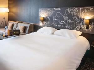 a large white bed with a wall with drawings on it at Ibis Styles Cognac in Châteaubernard +117 photos