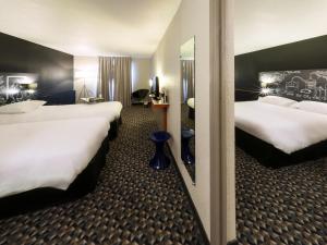 a hotel room with two beds and a mirror at Ibis Styles Cognac in Châteaubernard