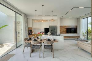 Snow White Villas 3BR Haven Near Pandawa Beach في أونغاسان: مطبخ وغرفة معيشة مع طاولة وكراسي