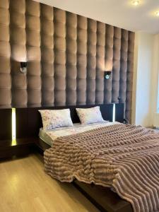 a bedroom with a large bed with a large padded wall at Мост сити АПП 151 с терассой in Dnipro