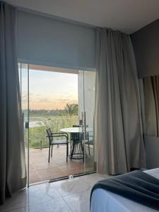 a bedroom with a bed and a balcony with a table at Villa brisa icaraizinho suíte premium 1 andar in Amontada
