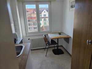 cocina con escritorio y silla frente a una ventana en Central studio apartment gratis Parkplatz, en St. Gallen 7 fotos más