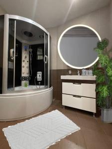 a bathroom with a large mirror and a white rug at Мост сити АПП 75 in Dnipro