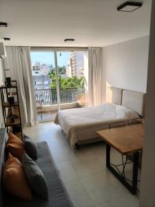 a bedroom with a bed and a table and a balcony at Departamento Estudio Deluxe in La Plata