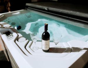 a bottle of wine and two wine glasses in a hot tub at Exquisite Cabin with Amazing Interior and Exterior in Sarahsville, Ohio in Senecaville