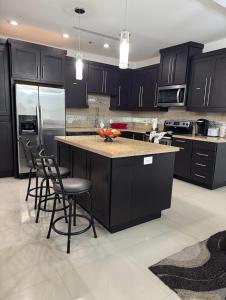 a kitchen with black cabinets and a island with bar stools at Fully Furnished 3BR and 2BA Gem Near Airport & Mall in McAllen